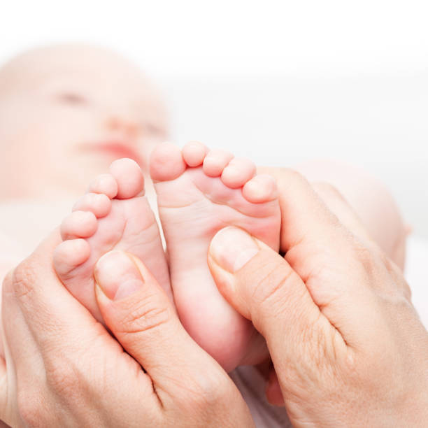 Close-up shot of three month baby girl's foot manipulated by osteopathic manual therapist or physician